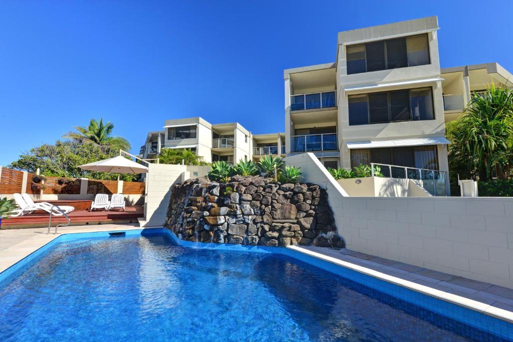 a swimming pool in front of a building at Bellardoo Holiday Apartments in Mooloolaba