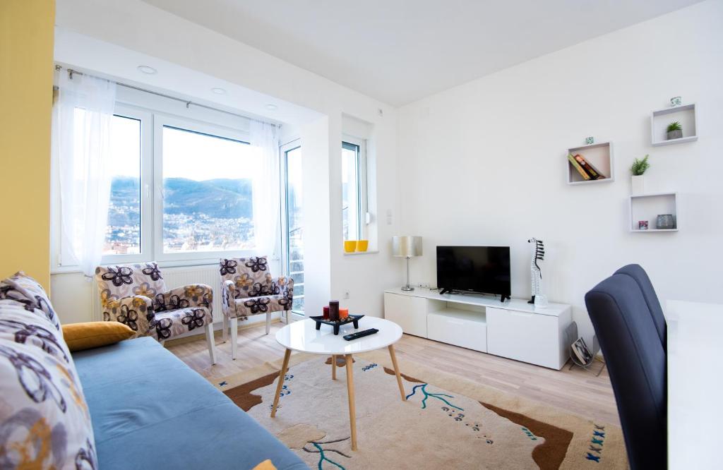 ein Wohnzimmer mit einem blauen Sofa und einem TV in der Unterkunft Sunrise Inn Sarajevo in Sarajevo