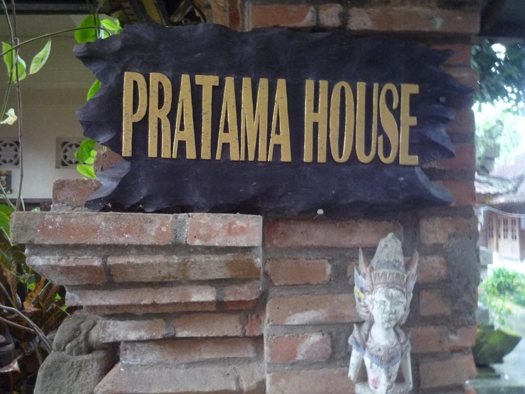 a sign for a pizzana house with a statue at Pratama house in Ubud