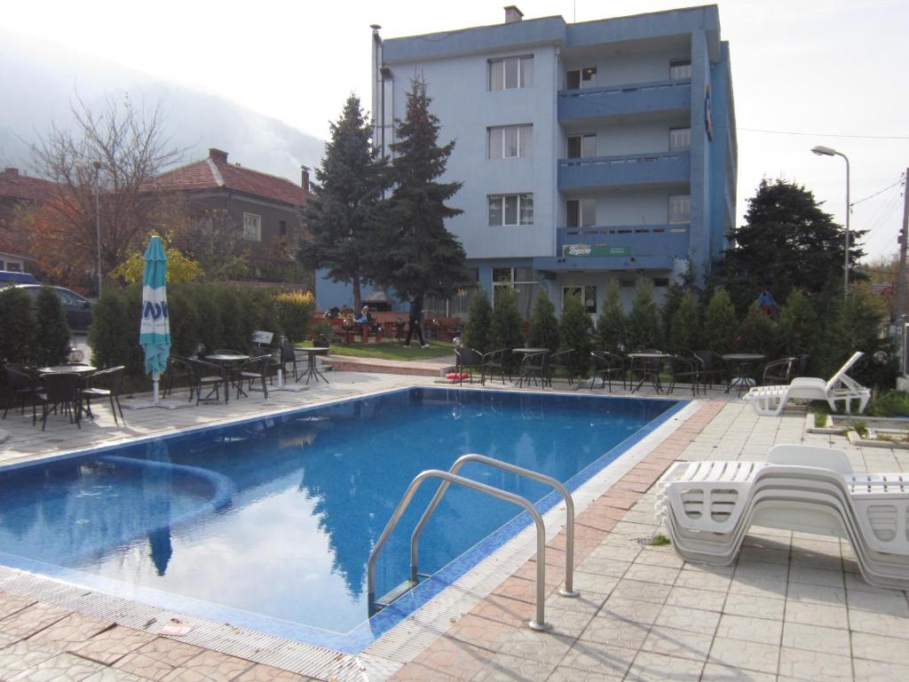 a swimming pool with chairs and tables and a building at Germanea Hotel in Sapareva Banya