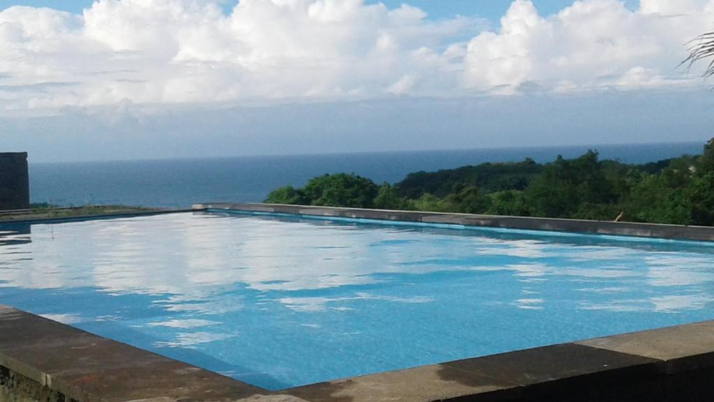 a swimming pool with the ocean in the background at Green Bowl Beach Villas in Uluwatu