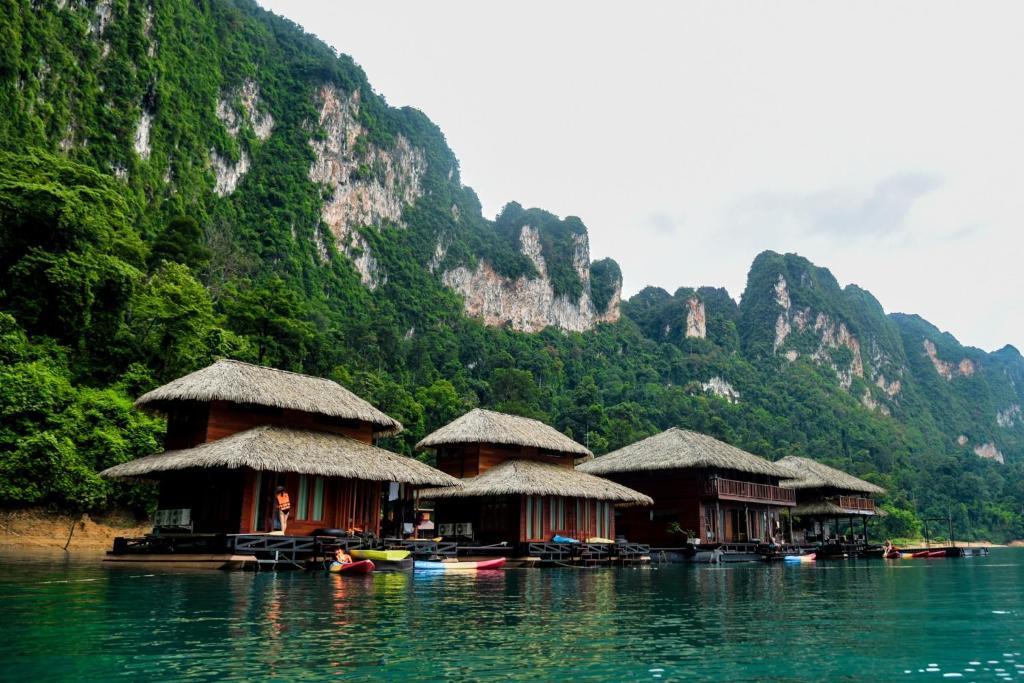 a group of huts on a body of water with mountains at Panvaree The Greenery in Ban Chieo Ko