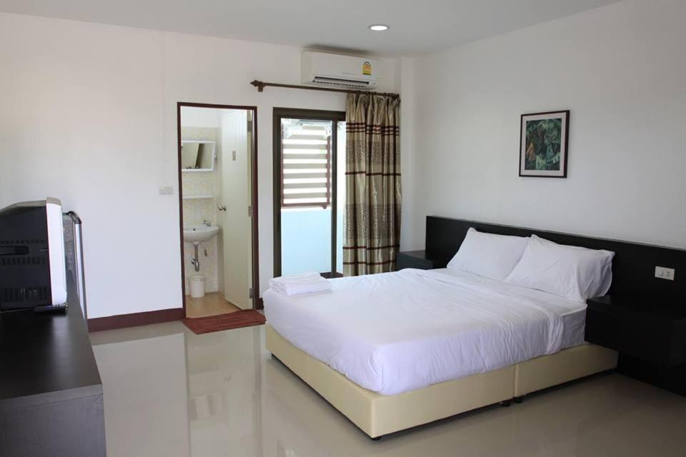 Un dormitorio con una gran cama blanca y un televisor. en Metha Palace, en Sakon Nakhon