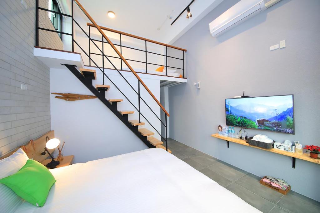 a room with a bed and a staircase and a tv at Qixingtan Xinghai B&amp;B in Dahan