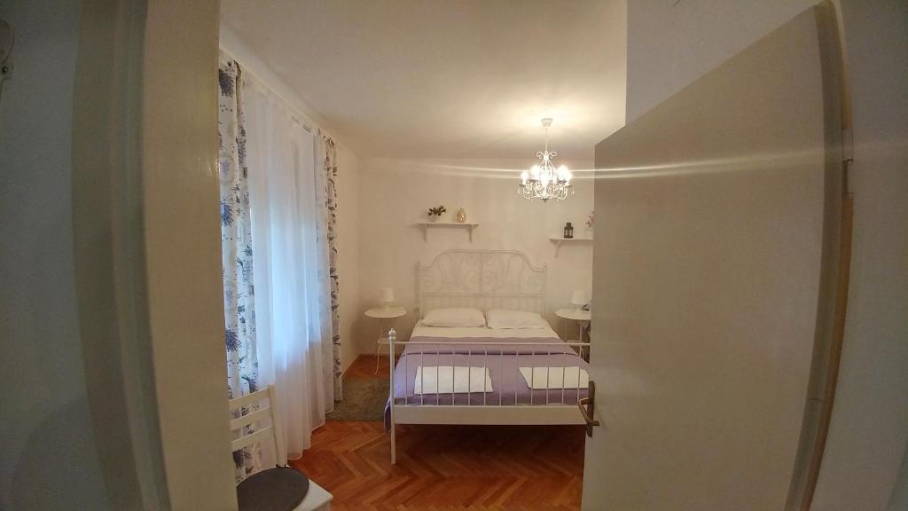 a small bedroom with a bed and a chandelier at APARTMANI RUŽICA in Crikvenica