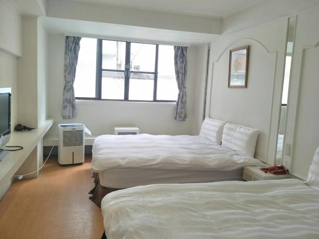 Cette chambre comprend deux lits et une télévision. dans l'établissement Maria Hotel, à Zhongzheng