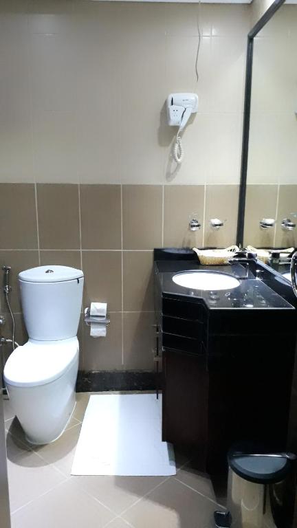 a bathroom with a toilet and a sink and a mirror at Hala Inn Hotel Apartments - BAITHANS in Ajman 