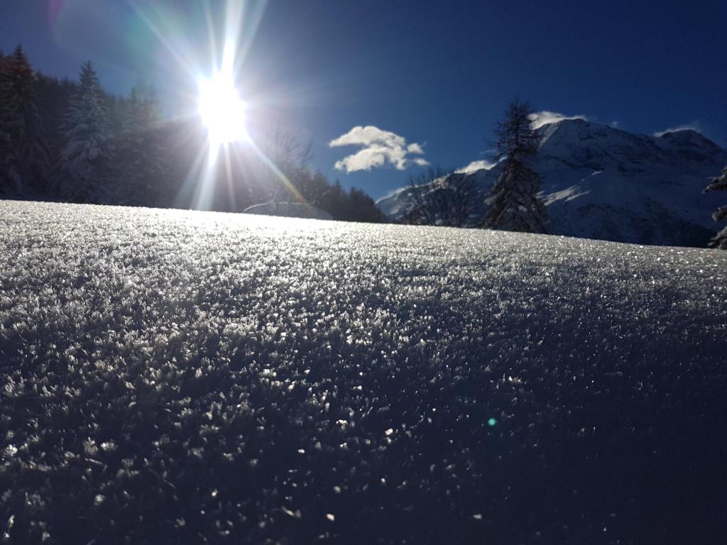 a snow covered slope with the sun in the background at Arpege Des Neiges in Sainte-Foy-Tarentaise