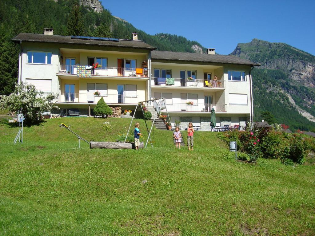 tre bambini che giocano in un campo di fronte a un edificio di Casa Agriturismo Mattei a Peccia