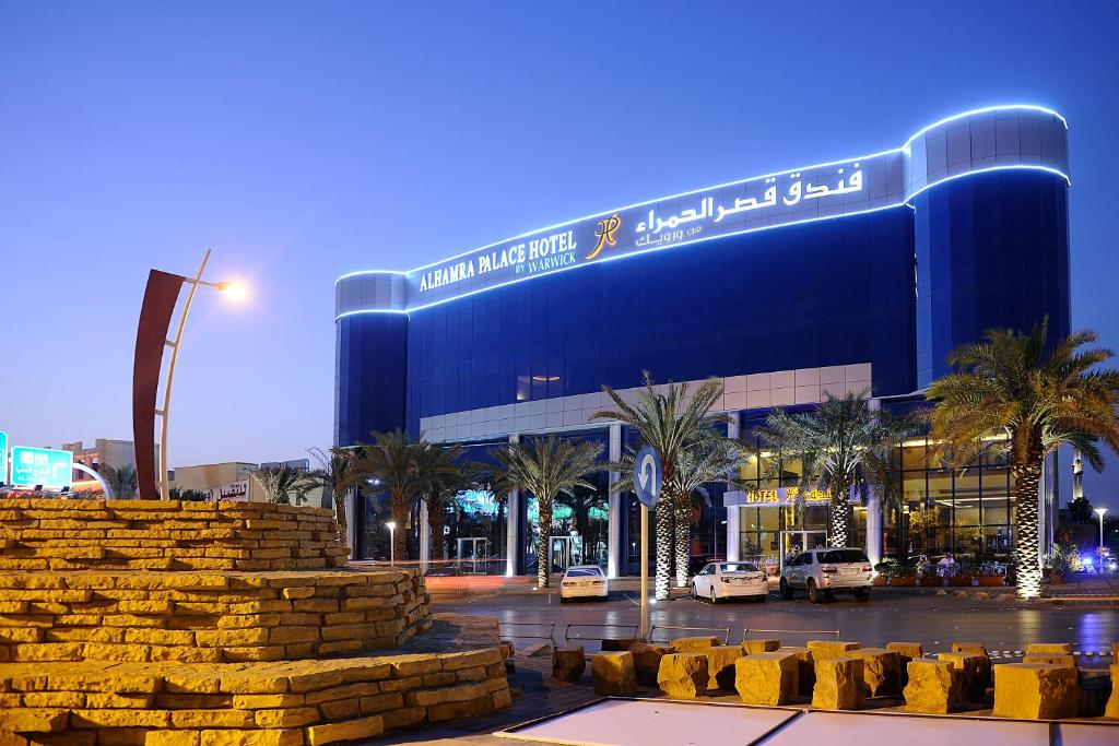 a large blue building with palm trees in front of it at Al Hamra Palace By Warwick in Riyadh