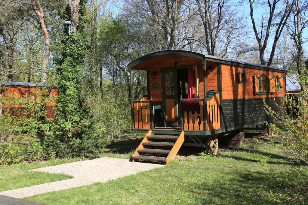 a tiny house in the woods with a porch and stairs at Roulottes de Bois le roi in Bois-le-Roi