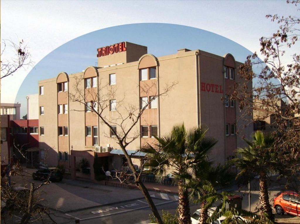 a large building with a sign on top of it at Hôtel Triotel in La Valette-du-Var