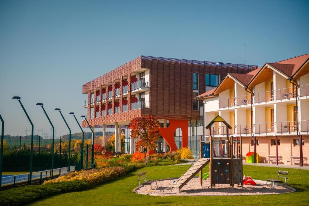 ein Gebäude mit einem Spielplatz vor einem Gebäude in der Unterkunft K-Triumf Resort in Velichovky