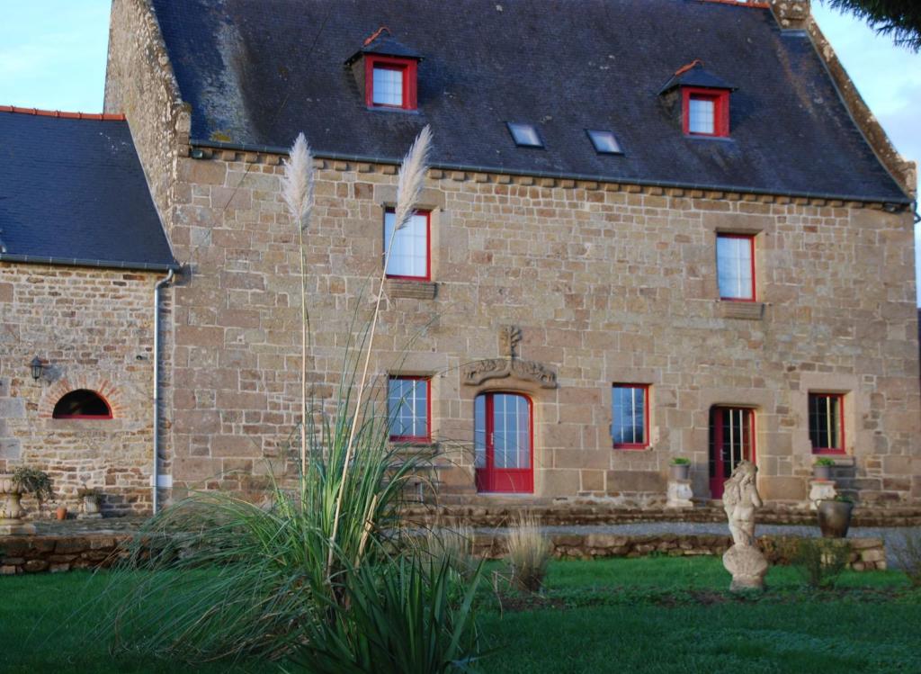 un gran edificio de piedra con puertas y ventanas rojas en Au Domaine de Rimou en Rimoux