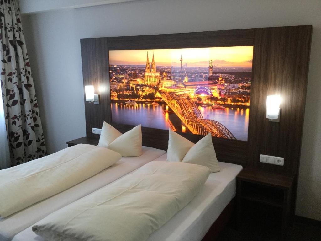 two beds in a room with a picture on the wall at Hotel Am Freischütz in Hürth