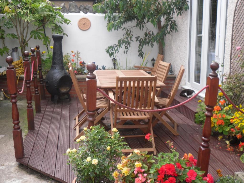 una terraza de madera con mesa, sillas y flores en The Gateway at Hest Bank, en Lancaster