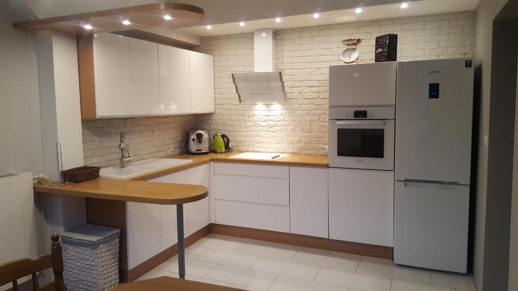 cocina con armarios blancos y nevera blanca en Apartament na Wolanach, en Polanica-Zdrój