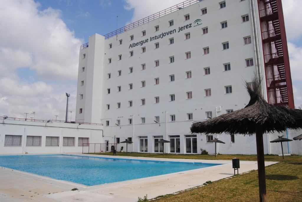 un hotel con piscina di fronte a un edificio di Albergue Inturjoven Jerez De La Frontera a Jerez de la Frontera