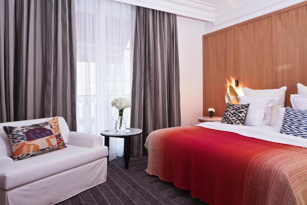 um quarto de hotel com uma cama e uma cadeira em Hôtel Vernet Champs Elysées Paris em Paris