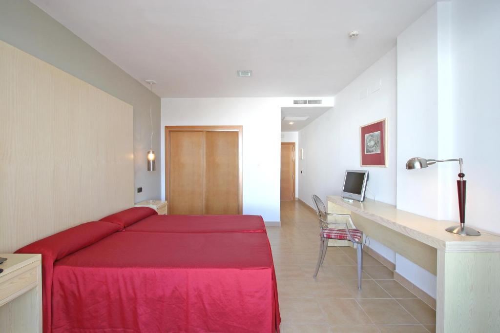 a bedroom with a red bed and a desk at Hotel Adiafa in Barbate