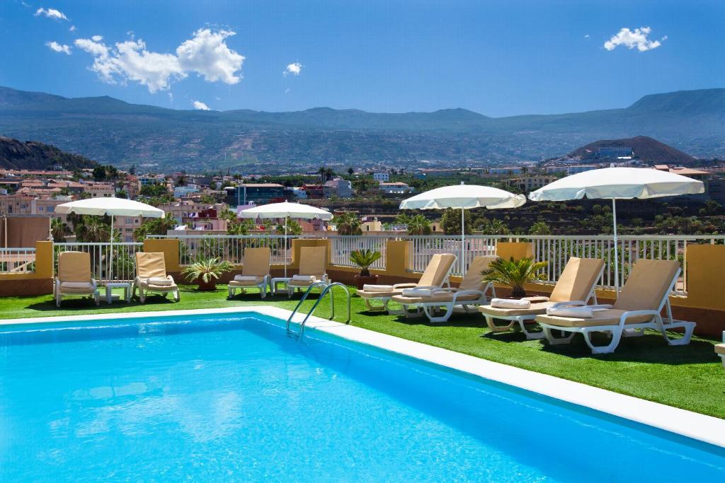 a swimming pool with chairs and umbrellas on a roof at GF Noelia in Puerto de la Cruz