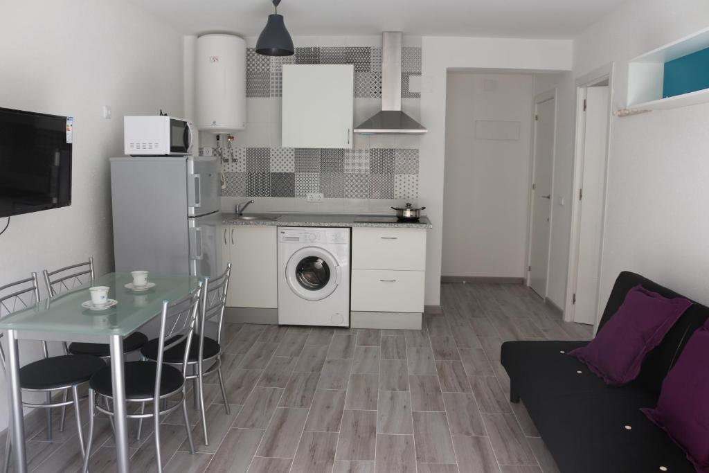 eine Küche und ein Wohnzimmer mit einem Tisch und einer Waschmaschine in der Unterkunft Temporary Alicante HM in Alicante