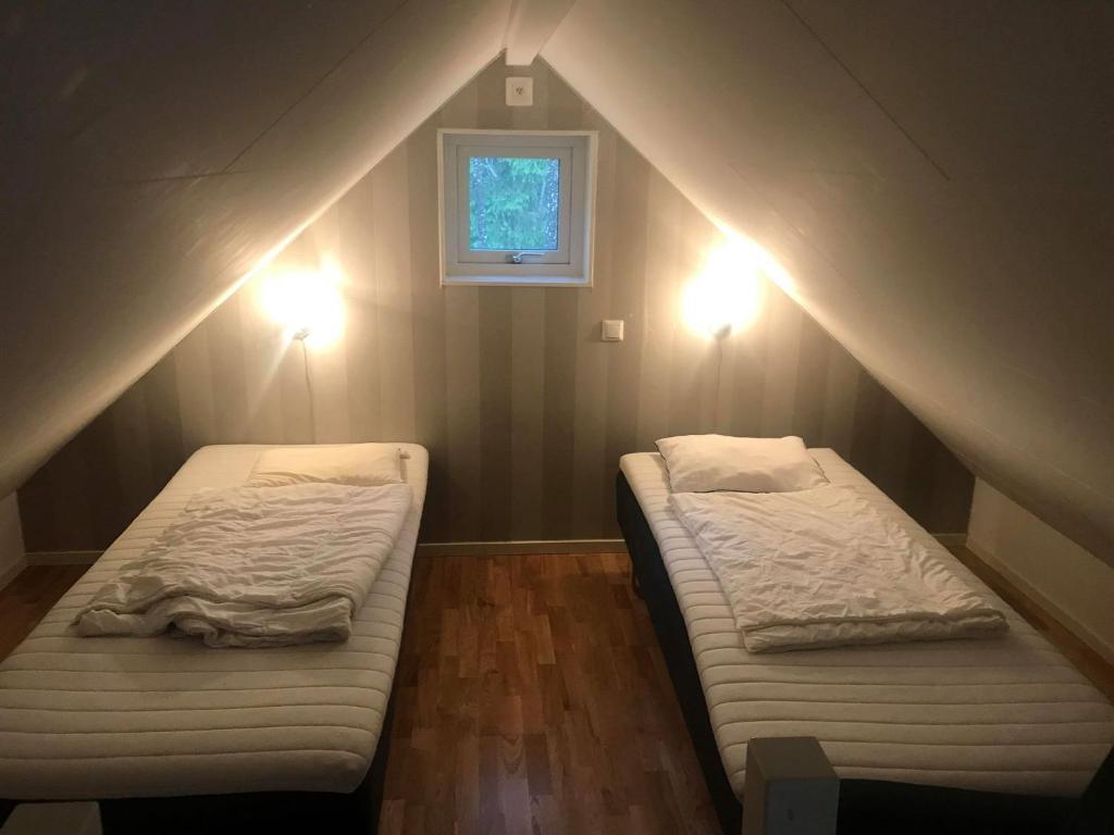 two beds in a room with a window and lights at Vilsta Camping and Cottages in Eskilstuna