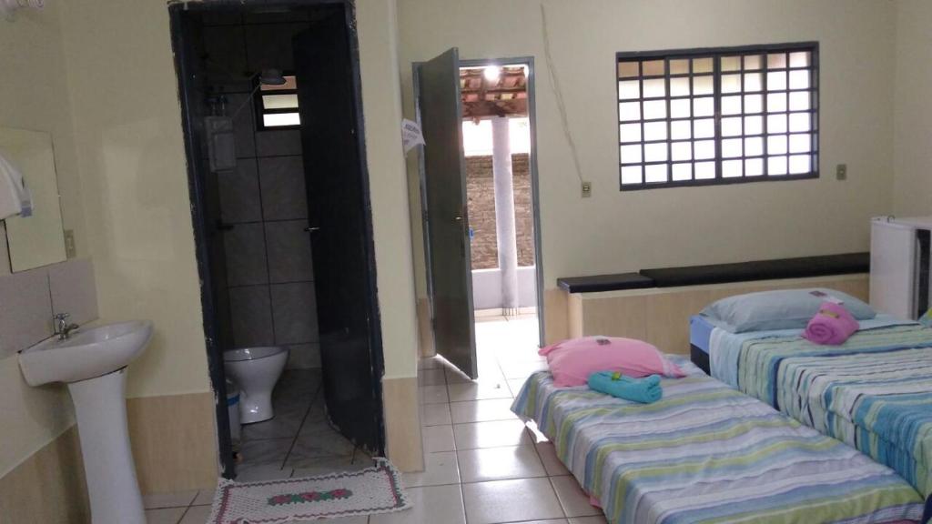 リオ・ケンテにあるPousada Agua Quenteのベッド2台、洗面台、バスルームが備わる客室です。