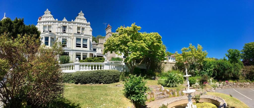 a large white house with a garden in front of it at Escape Boutique B&B in Llandudno