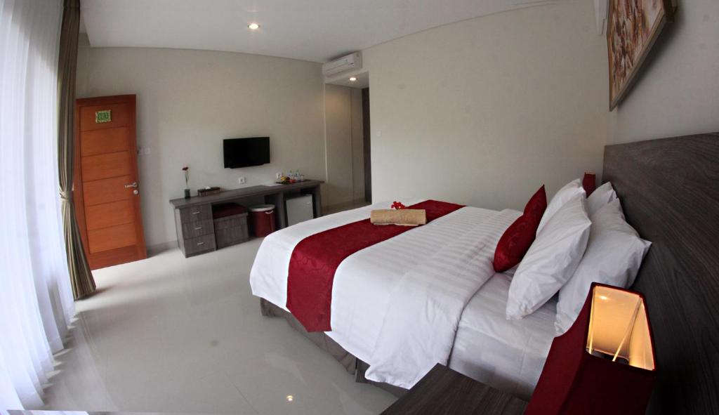 a bedroom with a large white bed with red pillows at Puri Kesari Guest House in Sanur