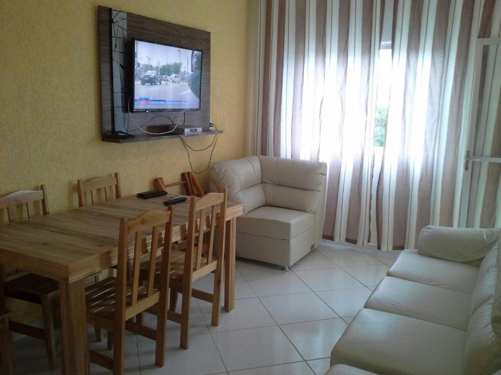 sala de estar con mesa, sofá y TV en Apartamento de temporada, en Bombinhas