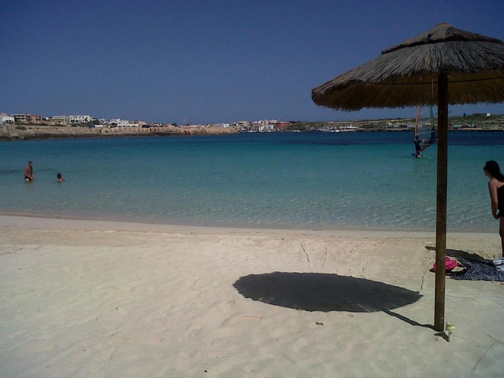 een schaduw van een rieten parasol op een strand bij Appartamento Guitgia in Lampedusa