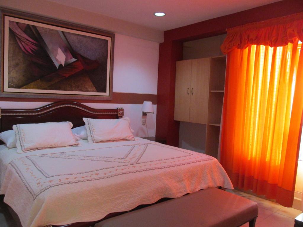 a bedroom with a large bed with an orange curtain at Rizzo Plaza Hotel in Tumbes