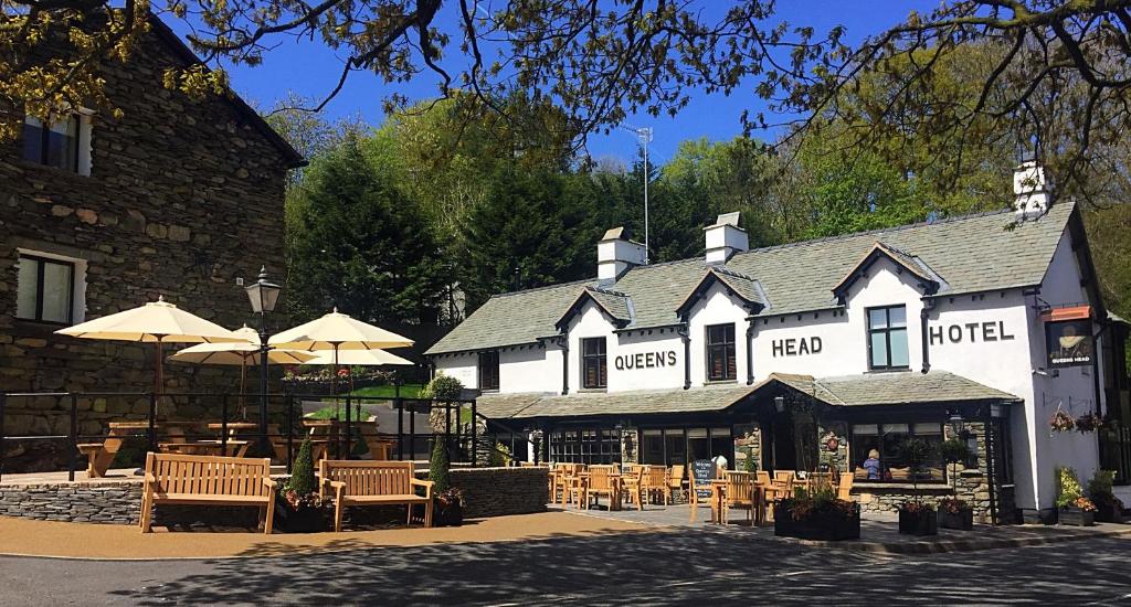 a hotel with tables and umbrellas in front of it at The Queen's Head Hotel in Troutbeck