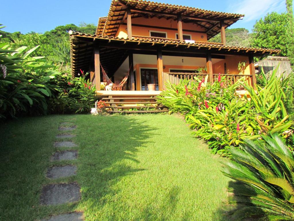 une maison avec une pelouse verte devant elle dans l'établissement Casa Praia de Santiago, à São Sebastião