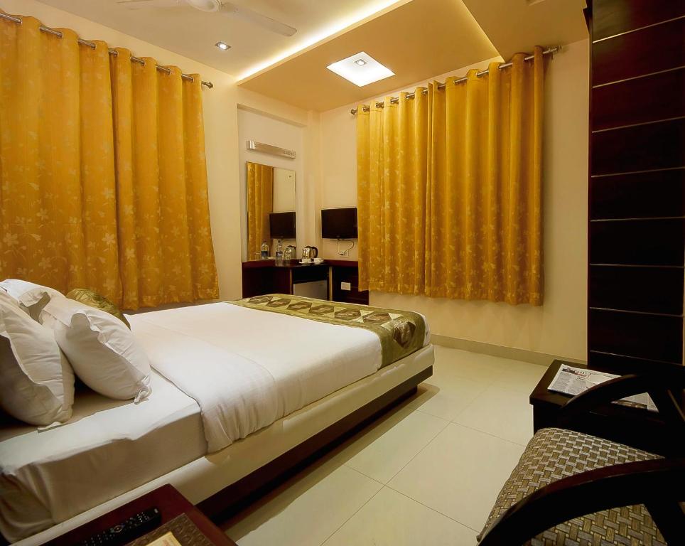a bedroom with yellow curtains and a large bed at Hotel Central Residency in Varanasi
