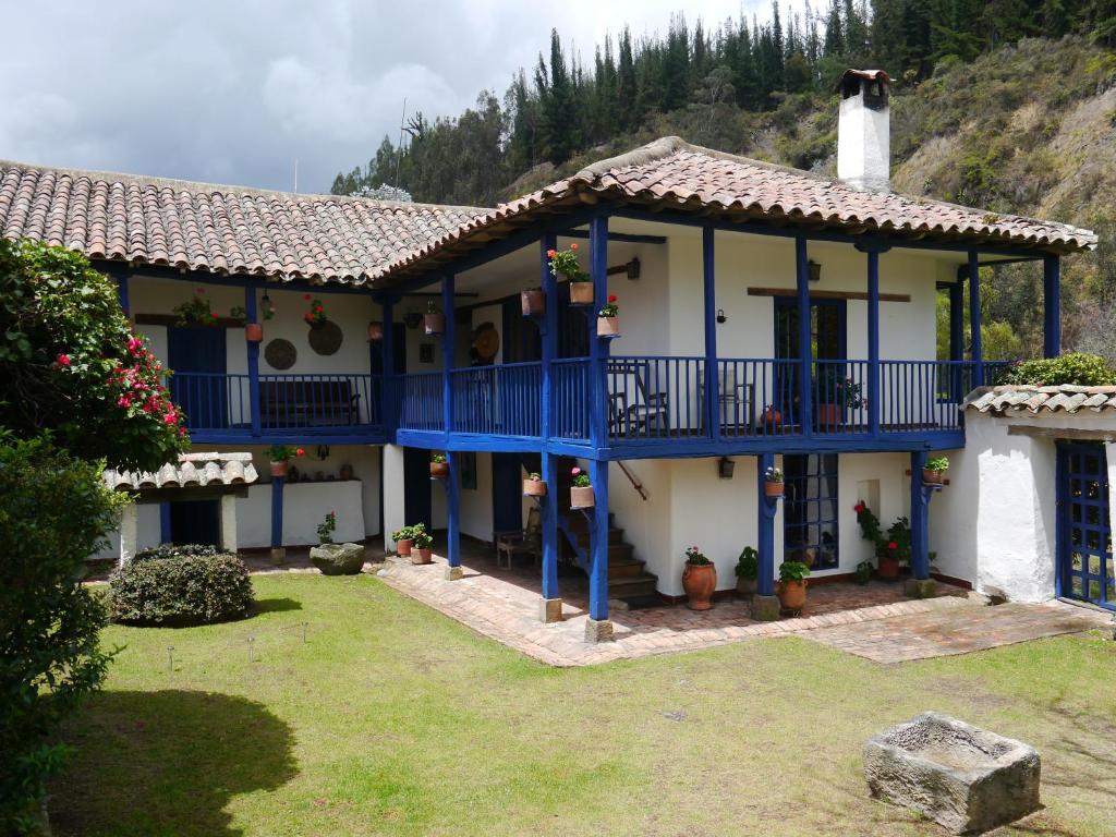 a house with a blue balcony and a yard at Posada El Molino de San Luis in Ubaté