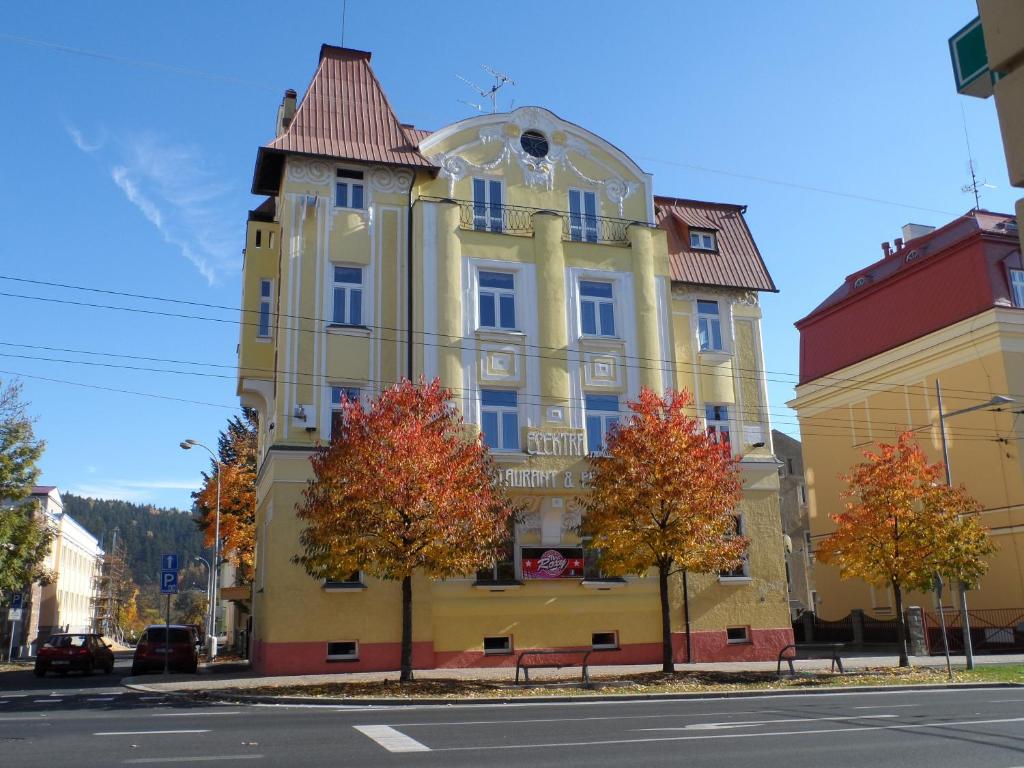 a yellow building with trees in front of it at Pension Elektra in Mariánské Lázně