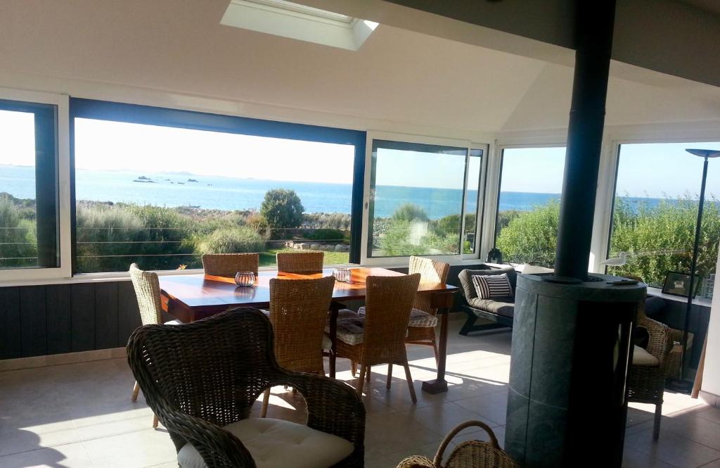 een eetkamer met een tafel, stoelen en ramen bij Seaview in Pleubian