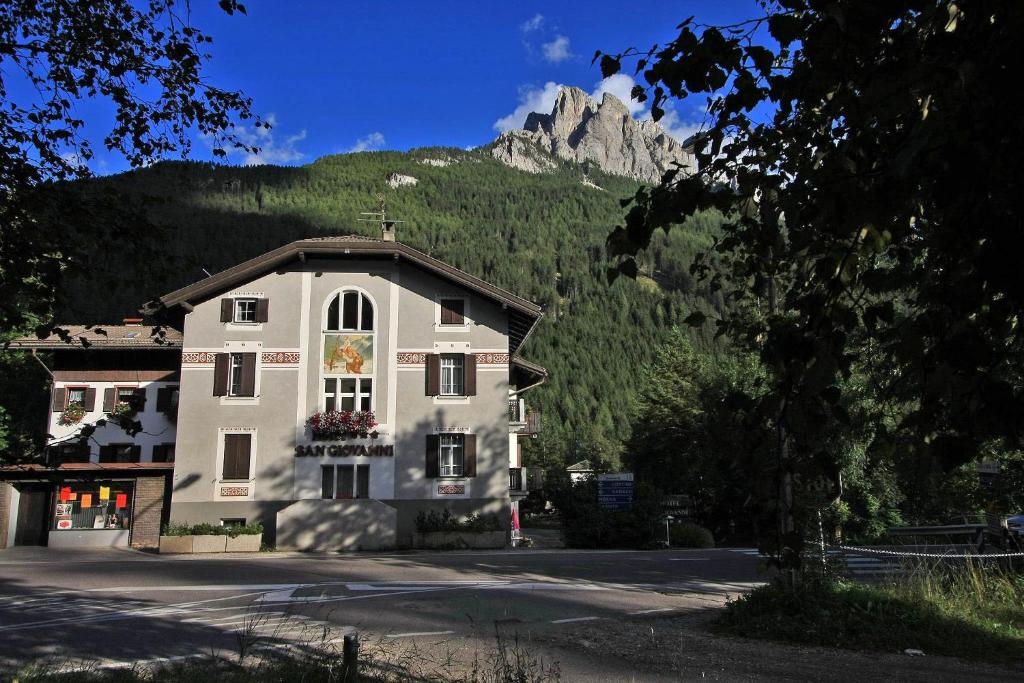 un grande edificio con una montagna sullo sfondo di Hotel San Giovanni a Vigo di Fassa