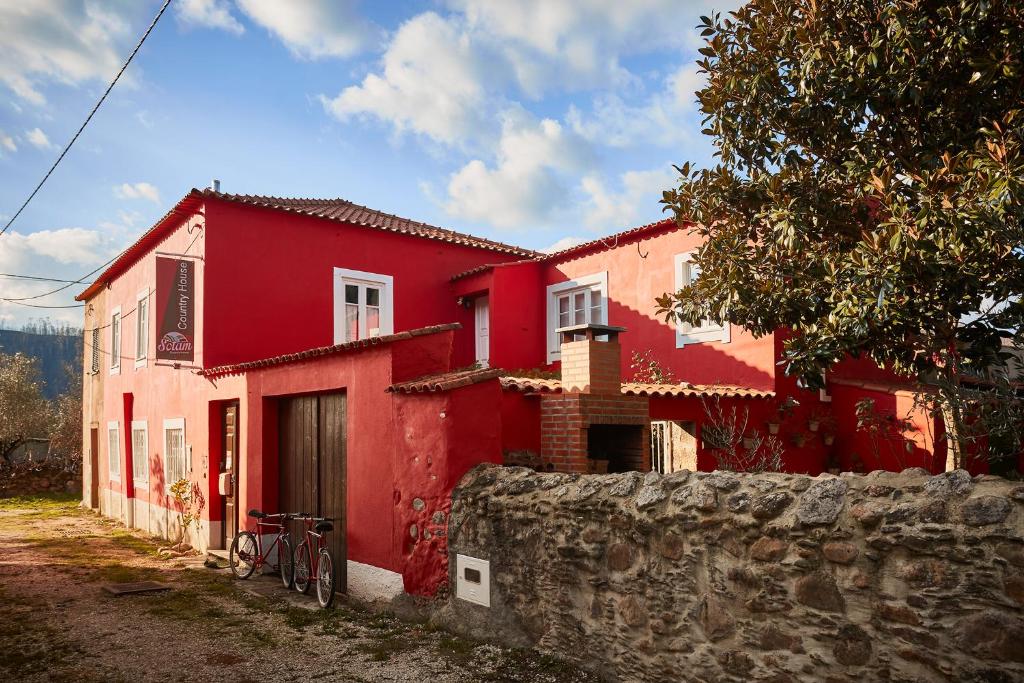 ein rotes Haus mit einem Fahrrad davor geparkt in der Unterkunft Sotam Country House in Góis