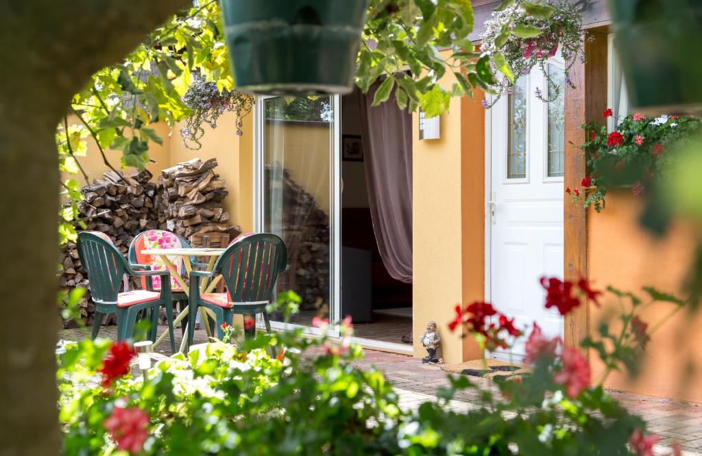 a patio with a table and chairs and flowers at Gîtes de Charme Chez Christine in Ottrott
