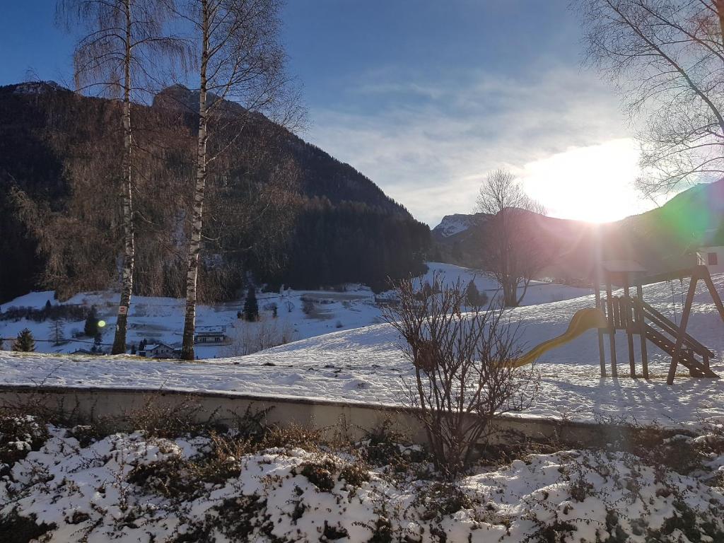 un campo cubierto de nieve con el sol en el fondo en Casa con vista a Moena, en Moena