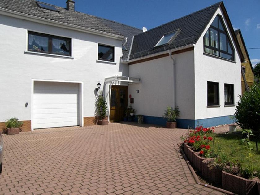 a white house with a garage and a brick driveway at Ferienwohnung Morbach in Morbach