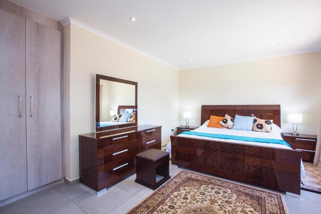 a bedroom with a large bed and a mirror at Chalet no. 2 Petunia in Johannesburg