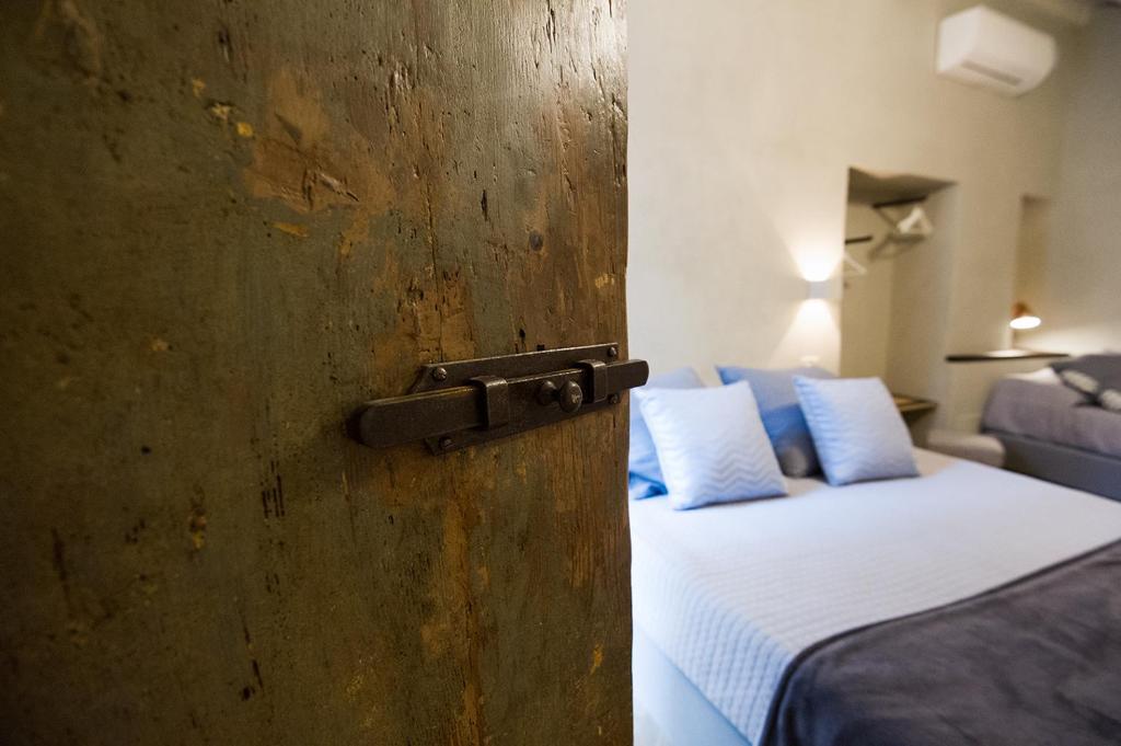 1 dormitorio con pared de madera y cama con almohadas azules en Il Piccolo Cavour Charming House B&B, en Arezzo