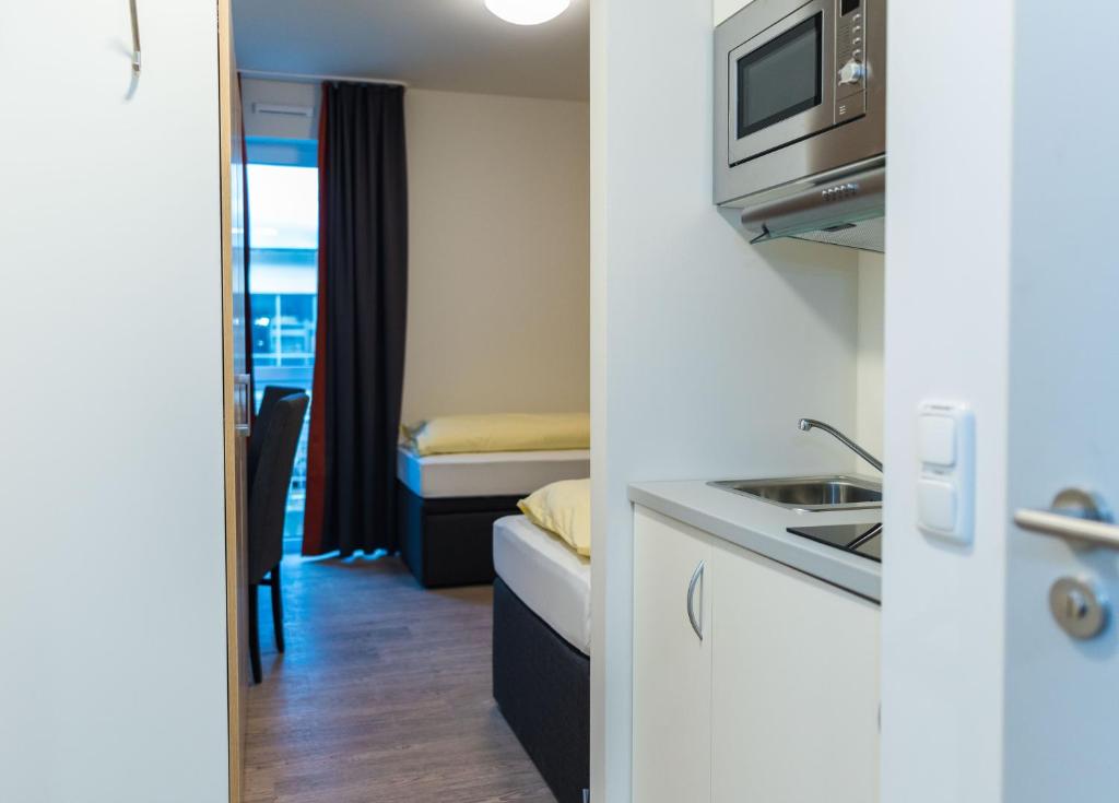 a small kitchen with a sink and a microwave at Hotel Staffelseestraße in Munich