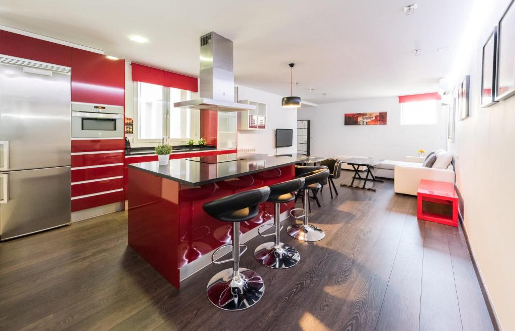 eine Küche mit roten Schränken und eine Bar mit Hockern in der Unterkunft Living Carretas in Madrid