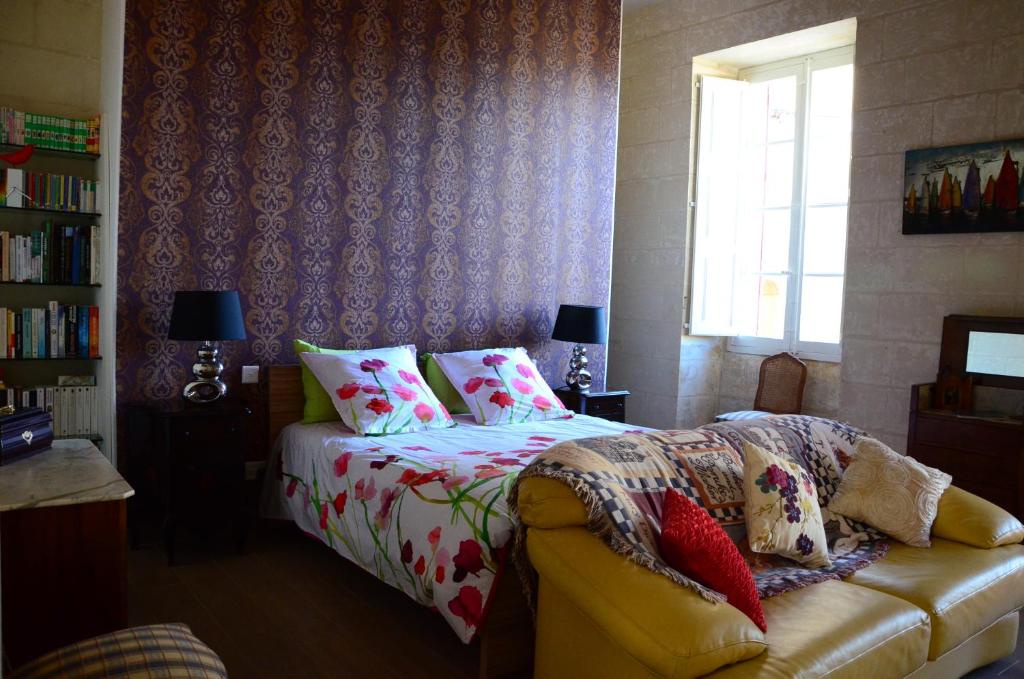 ein Schlafzimmer mit einem Bett, einem Sofa und einem Fenster in der Unterkunft Palazzio 1787 in Żejtun