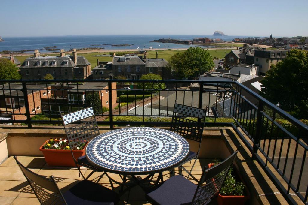 una mesa y sillas en un balcón con vistas al océano en No 10 Royal Apartments, en North Berwick